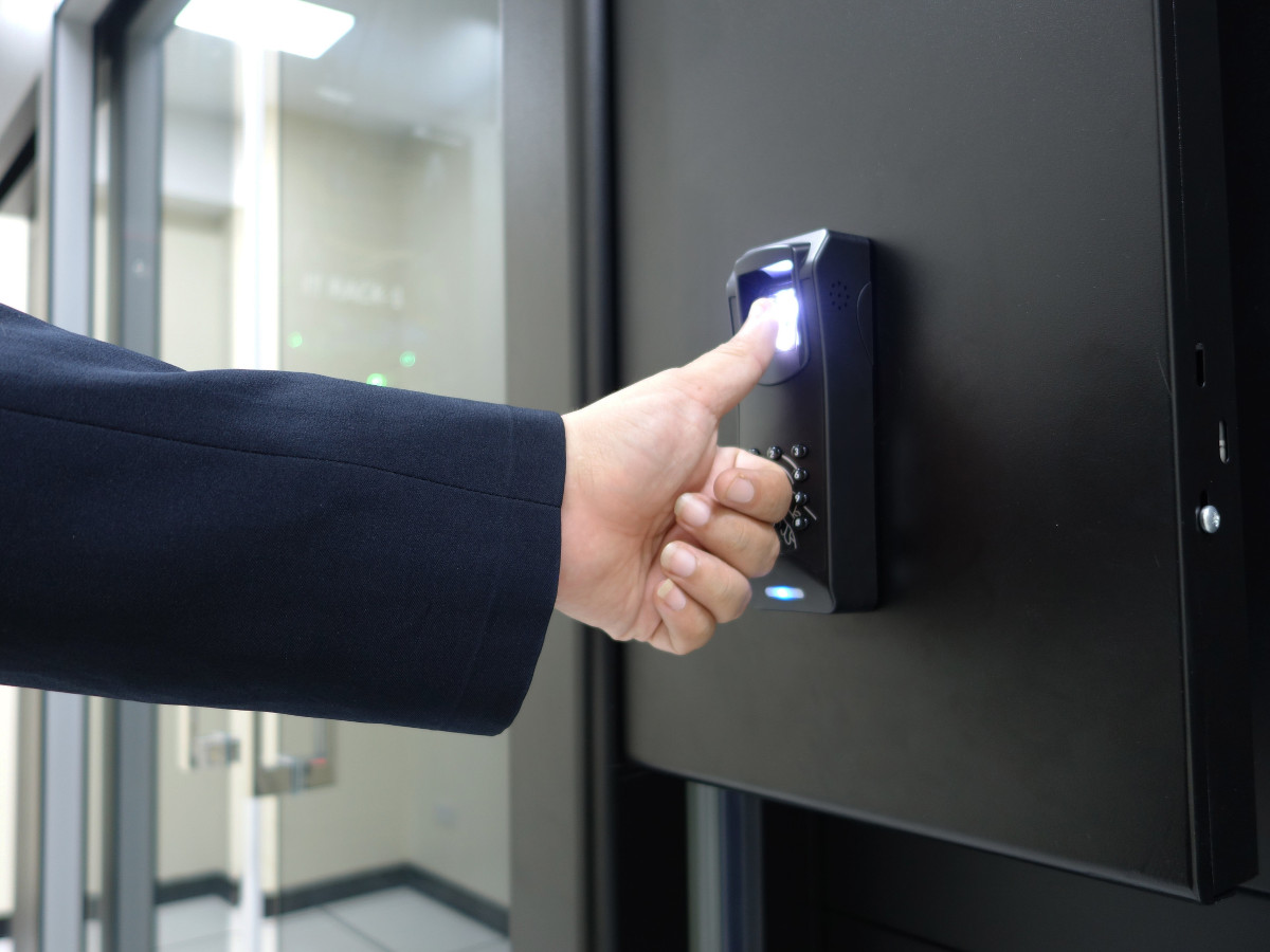 A man pressing his thumb on a biometric access control panel
