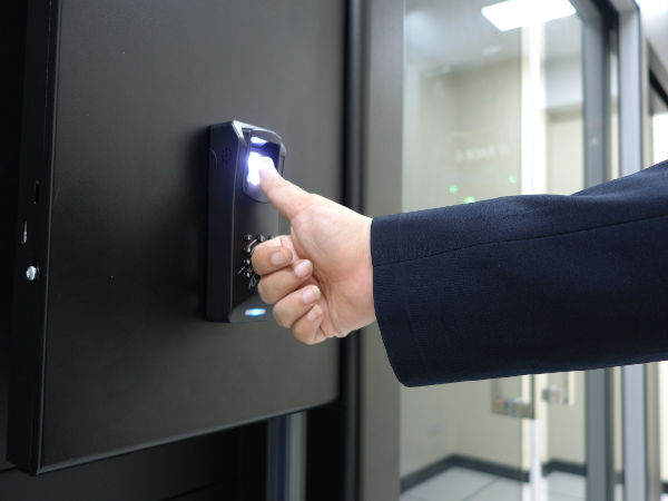 Hand using a thumbprint scanner on a modern secure access control system