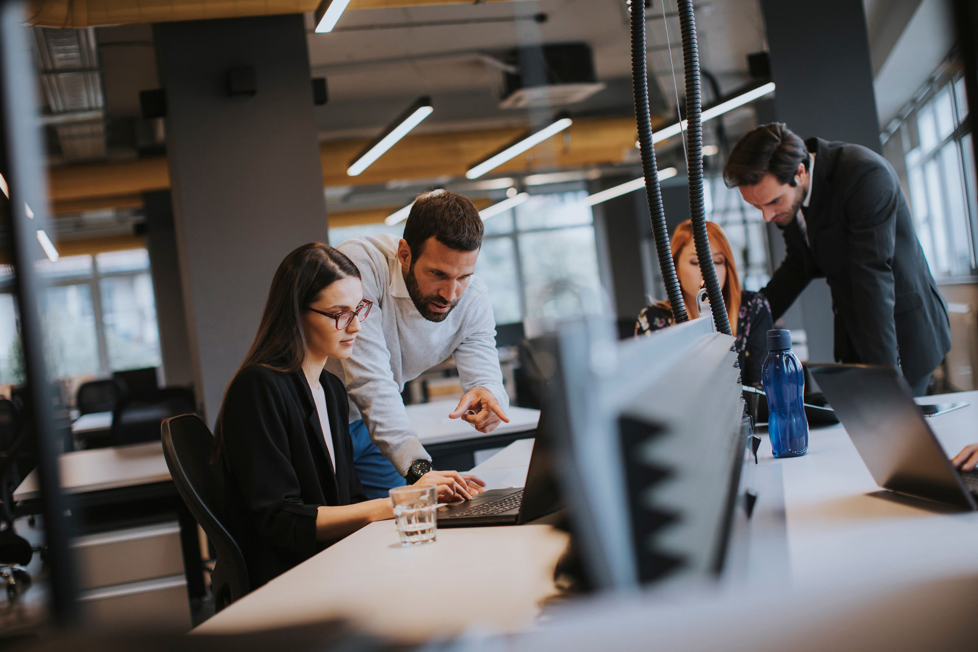 Group of young business people working together around a desk with laptops