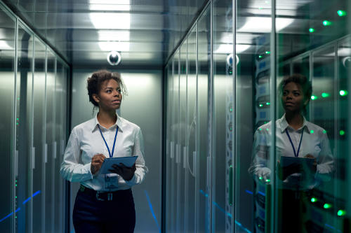 Woman on tablet walking in data center corridor