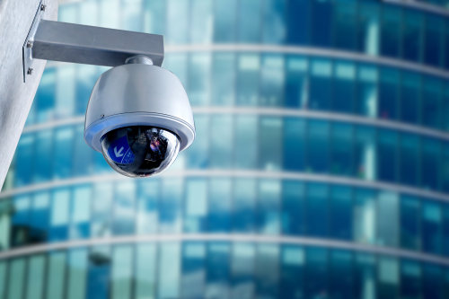 Close-up of a rounded security camera infront of a modern office building