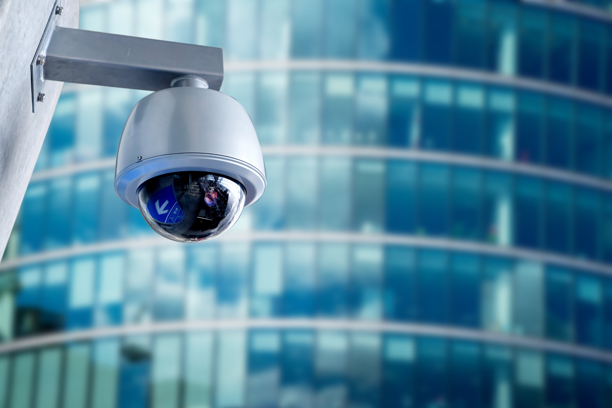 Close-up of a rounded security camera infront of a modern office building