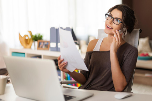 Young woman on cell phone working remotely from home office