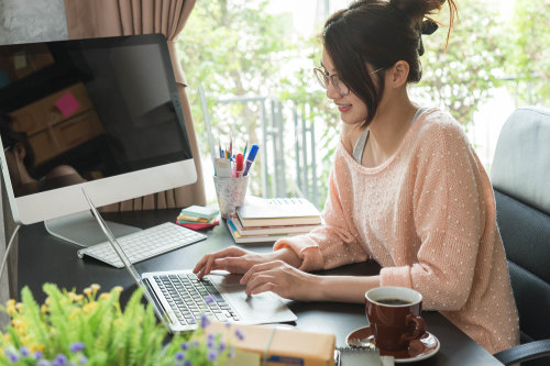 Young woman working on laptop from her home office